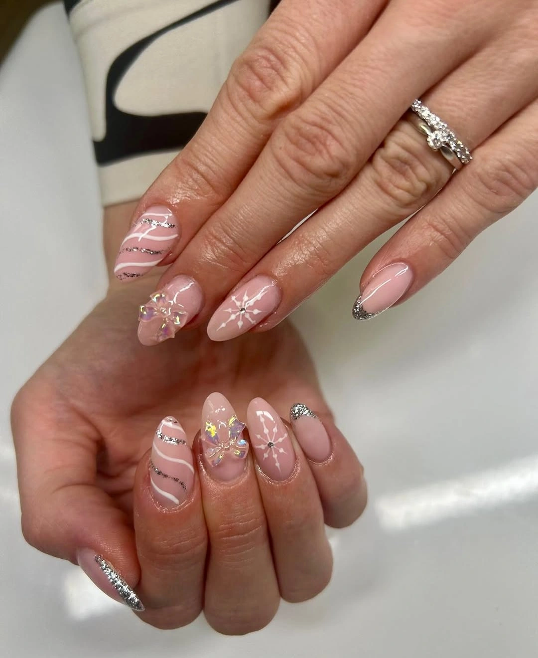 Pink almond nails with silver curves and iridescent raised accents