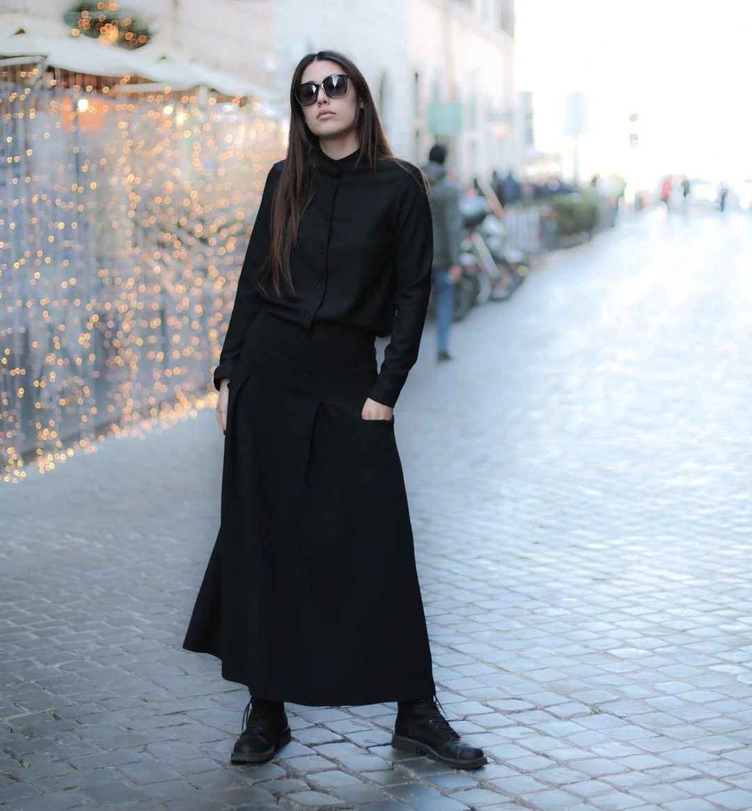 All-black outfit with long skirt, dark upper layer, and lace-up boots