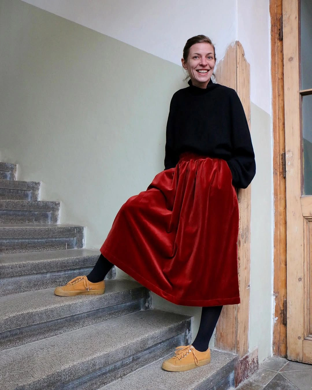 Black sweater with glossy red midi skirt, tights, and tan shoes