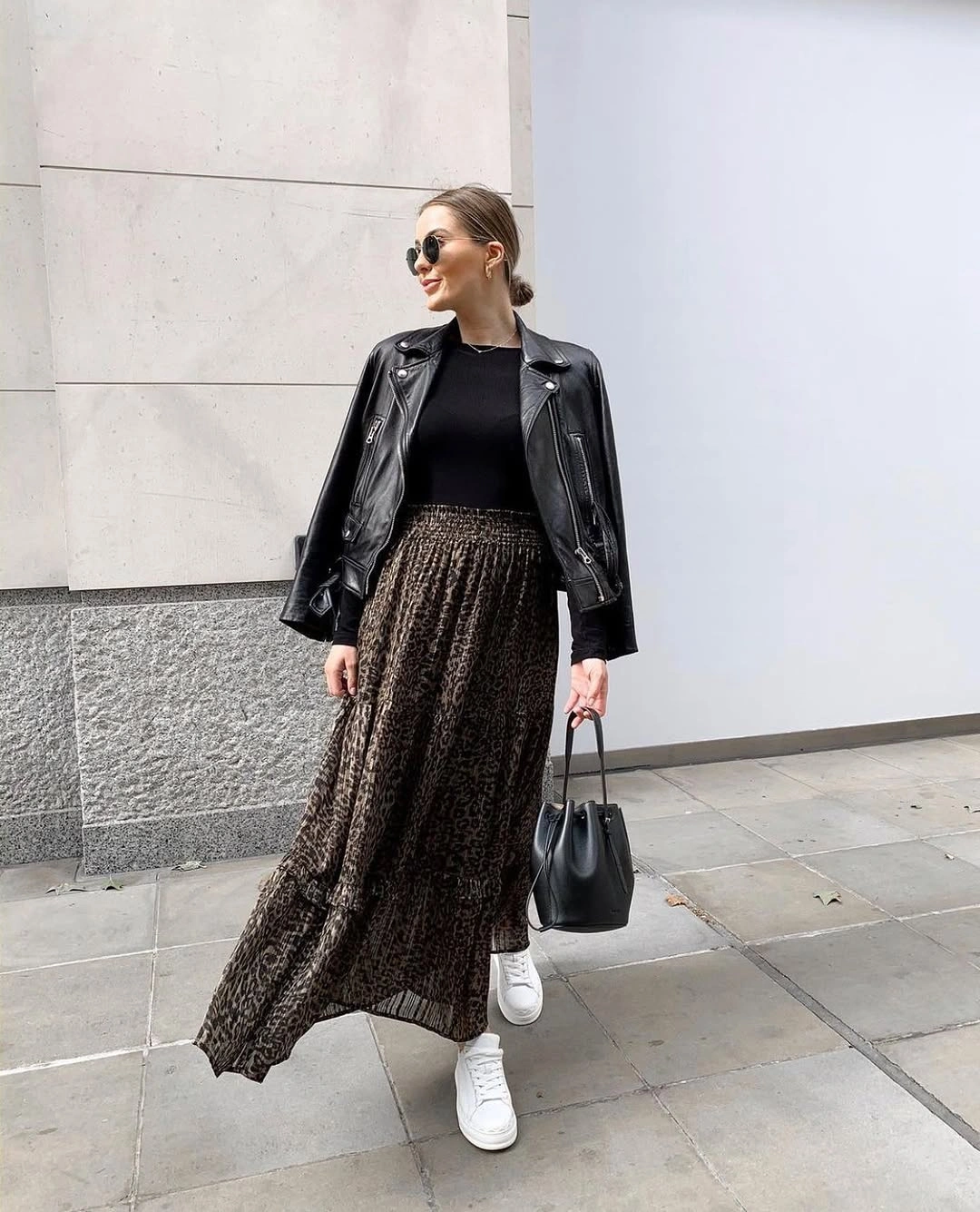 Leather-looking black jacket over animal-print skirt with white sneakers