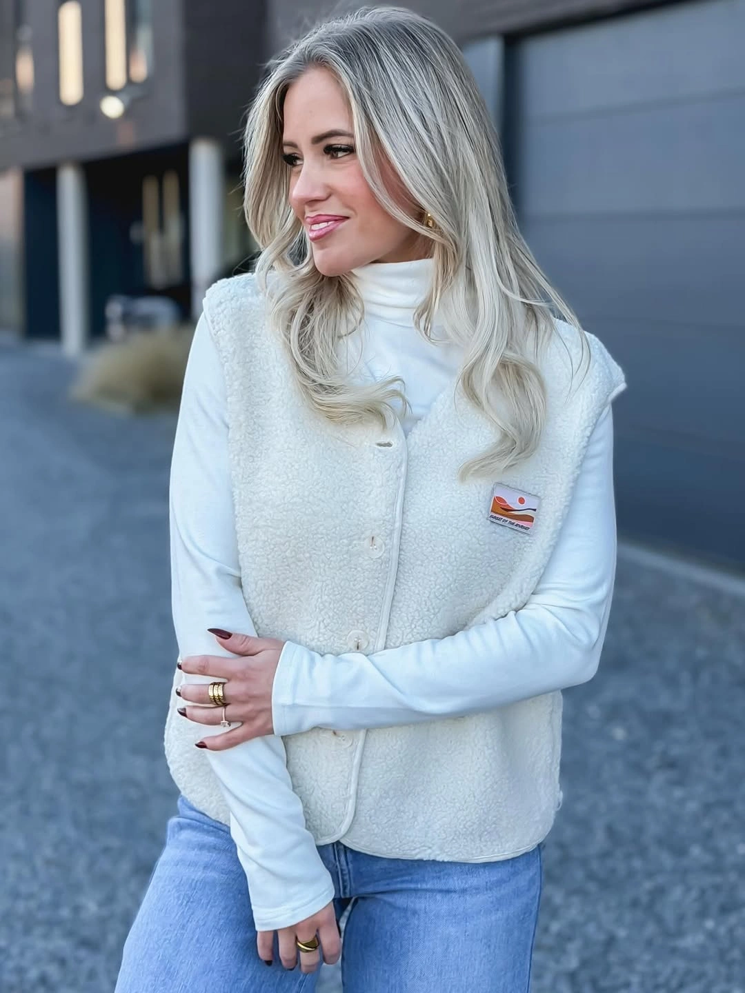 Ivory textured button front vest over white turtleneck and blue jeans