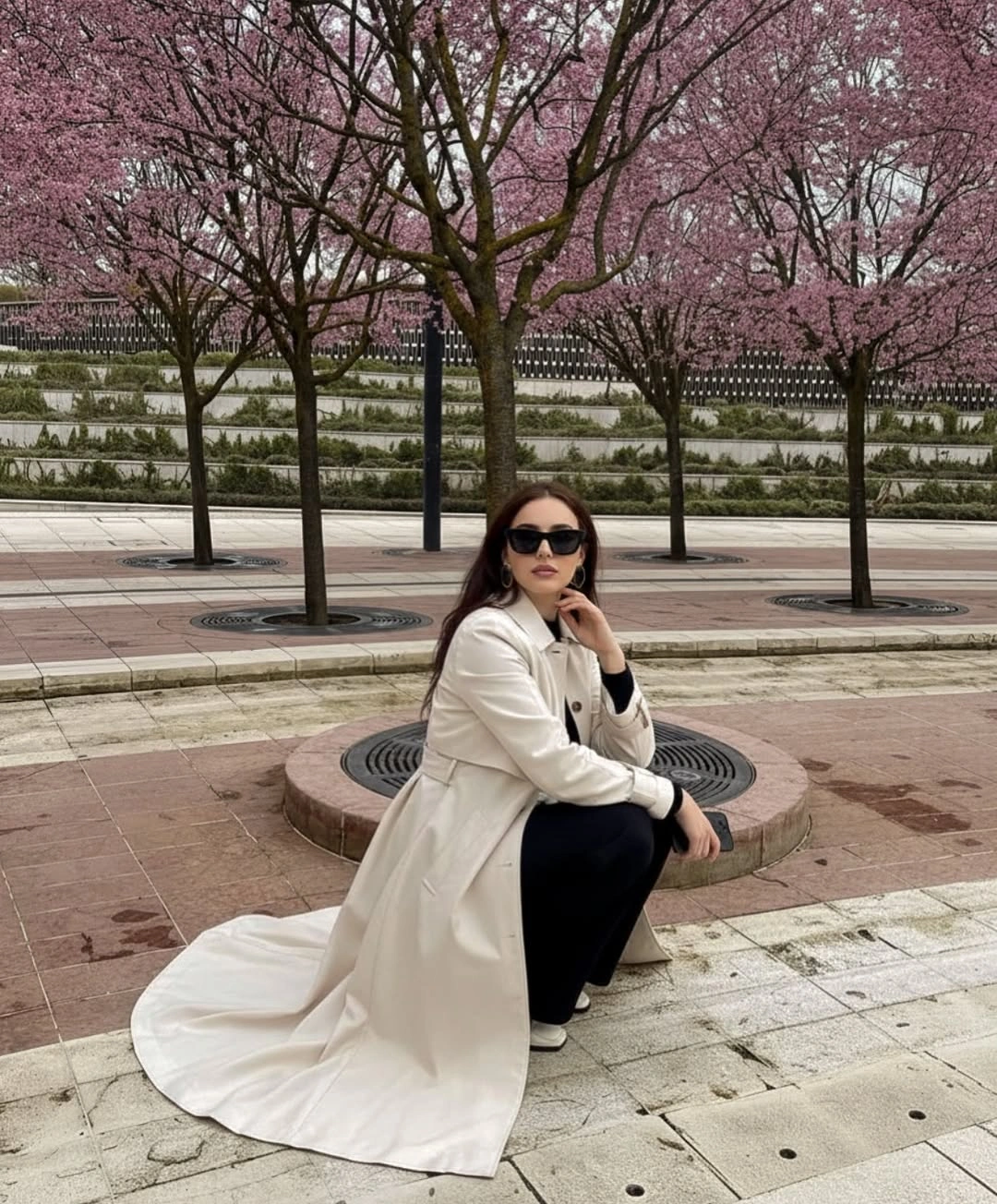 Long cream trench coat with dark clothing and black sunglasses