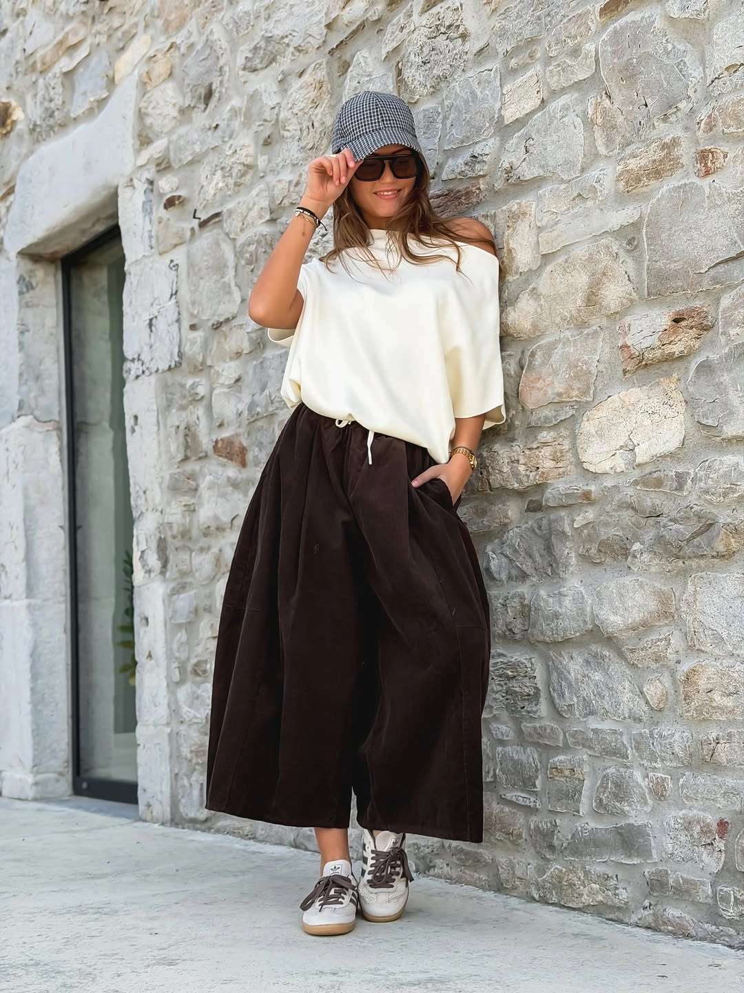 Loose ivory top with wide cropped brown trousers cap and sneakers