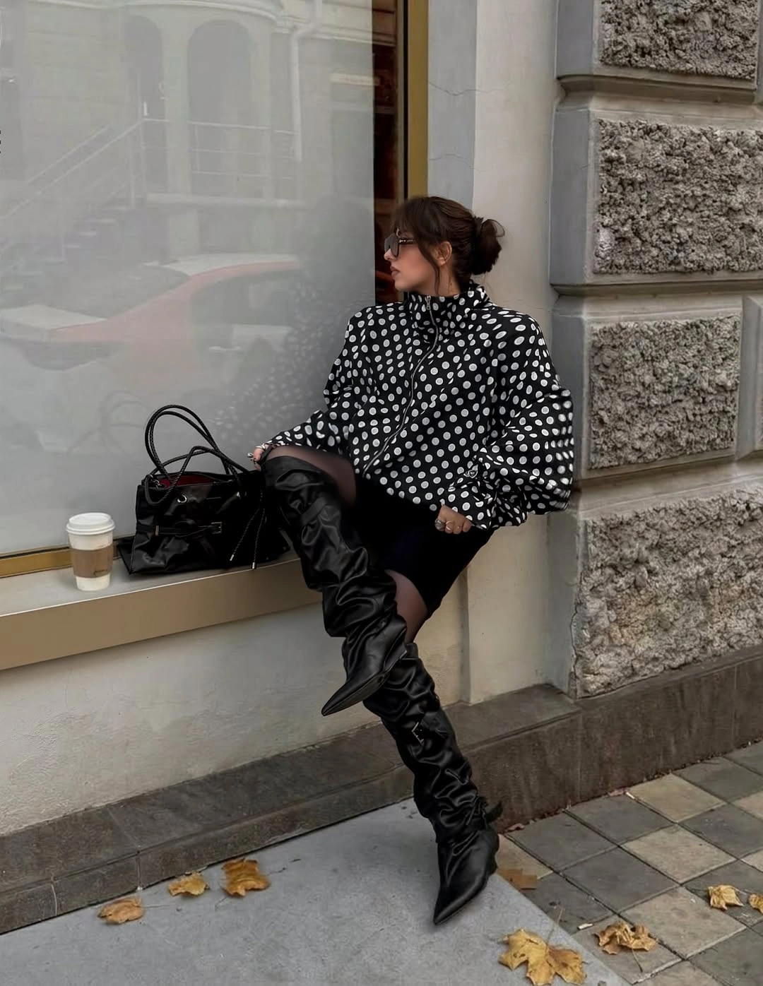 Spotted black blouse with short black bottoms and tall pointed boots