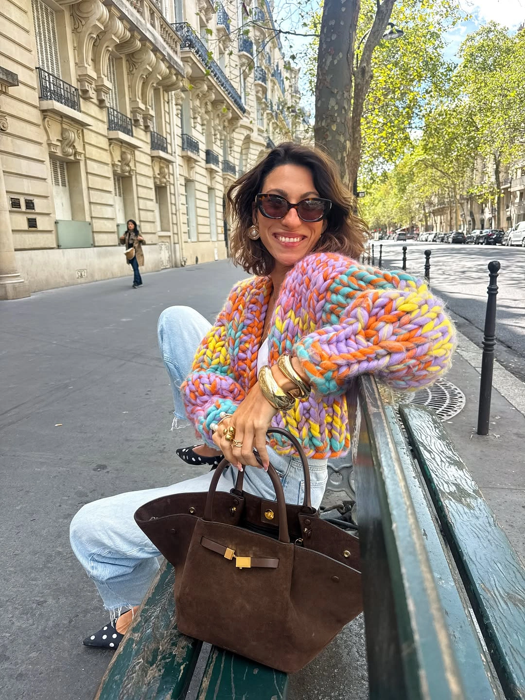 Multicolored chunky knit sweater with blue jeans and oversized brown handbag