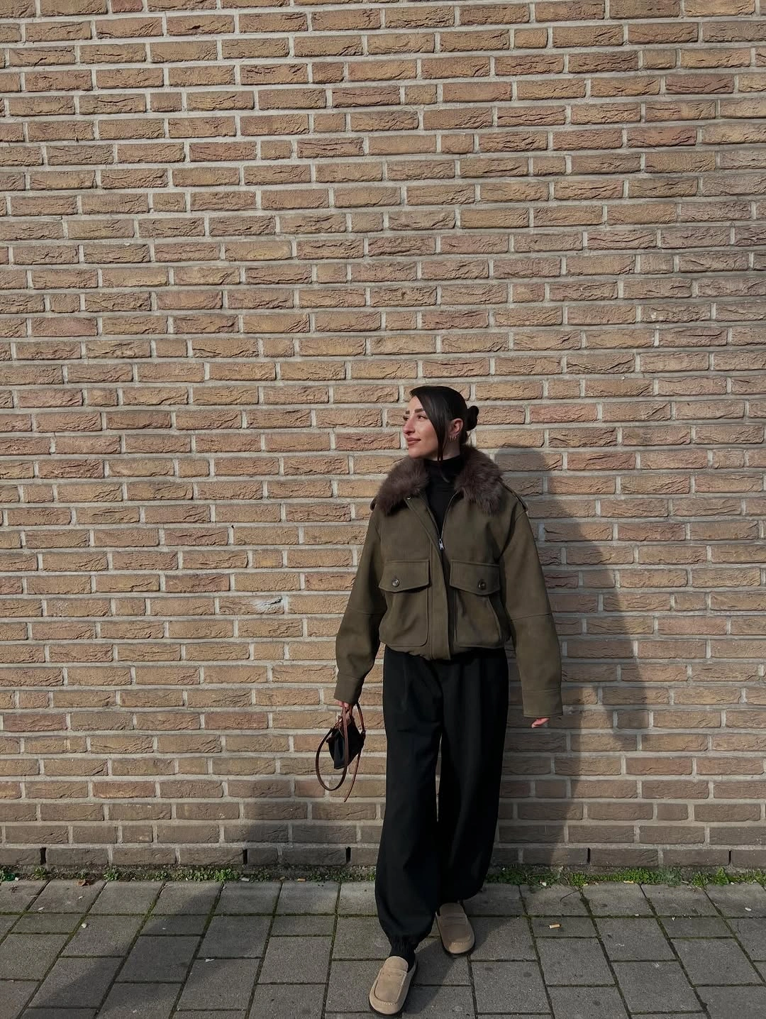 Olive utility jacket with dark collar loose black trousers and tan shoes
