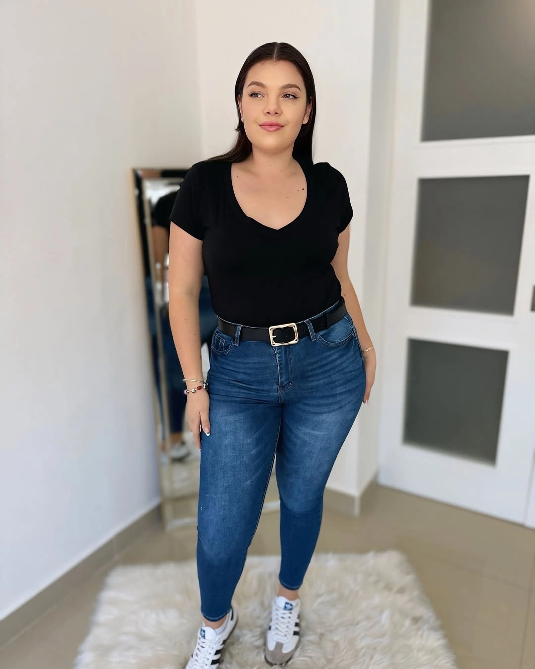 Black V-neck tee with blue jeans and white sneakers