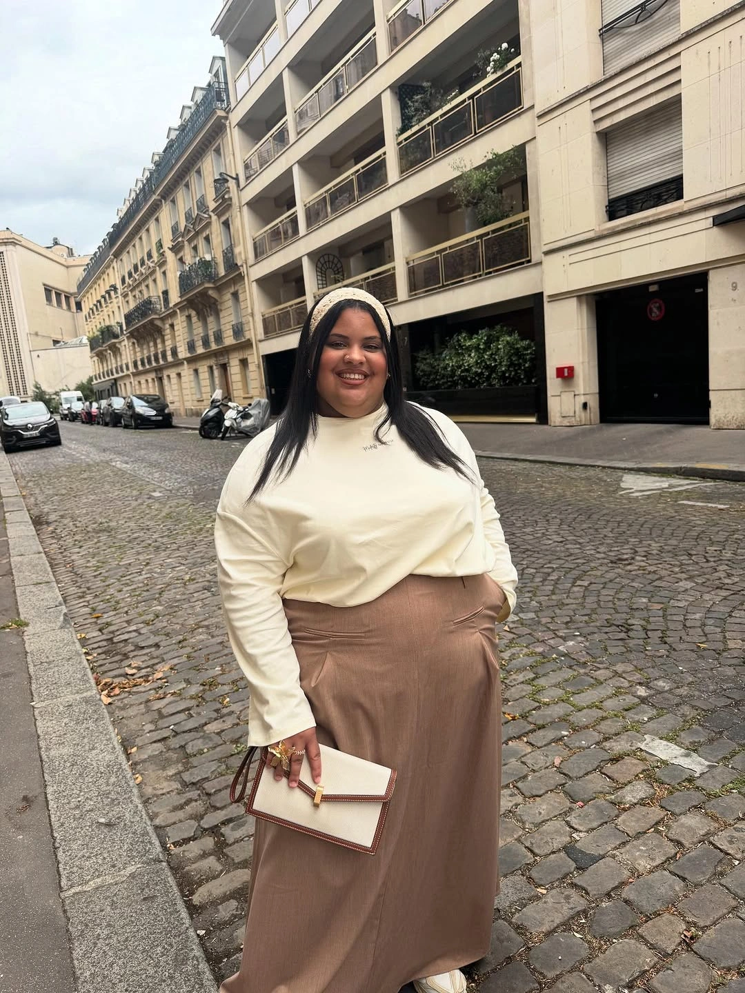 Cream sweater with long taupe lower piece and clutch