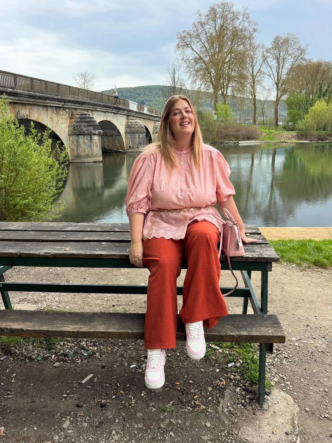 Pink puff-sleeve blouse with rust trousers and white sneakers