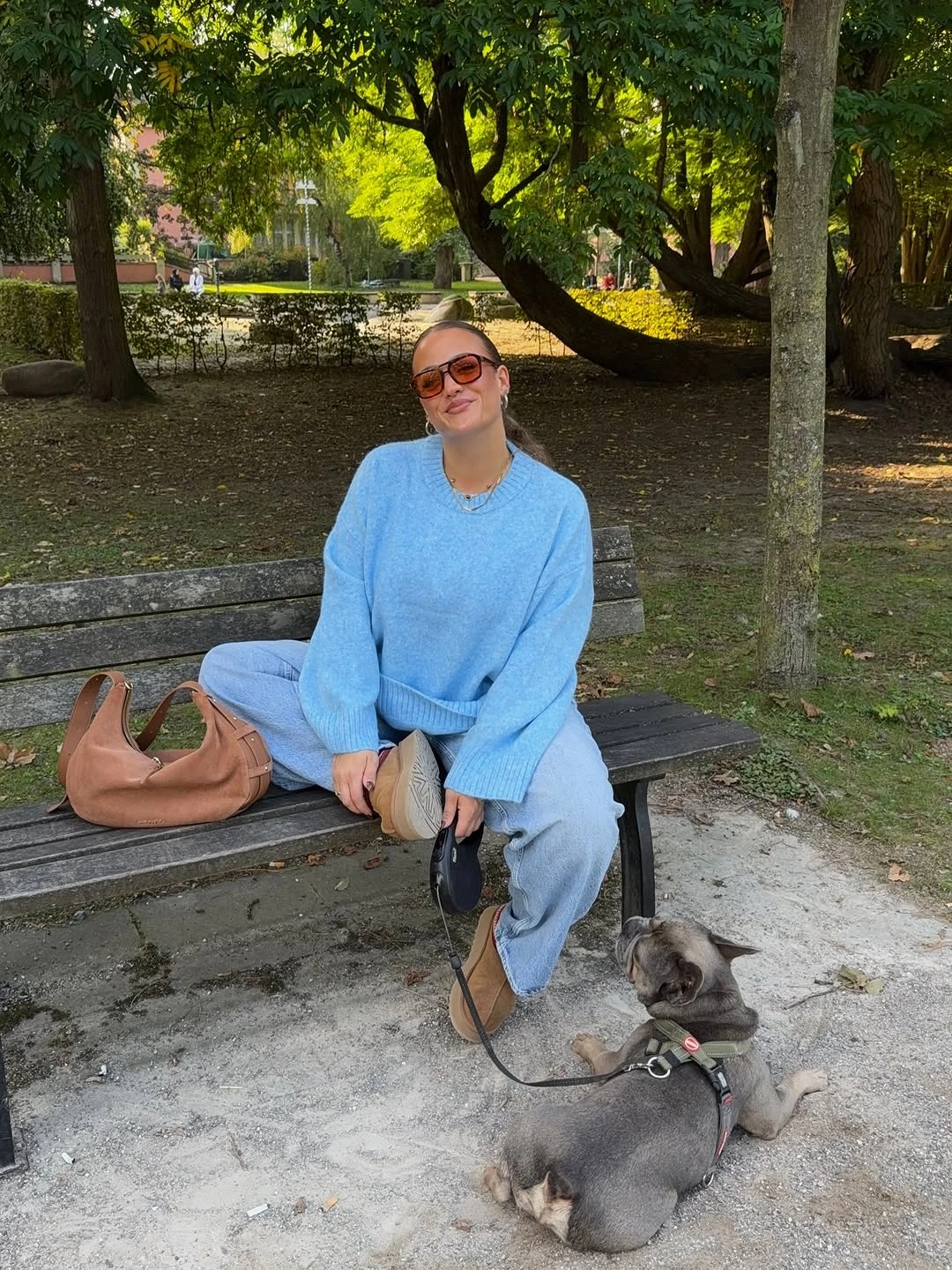 Powder blue sweater with pale denim and tan crescent bag