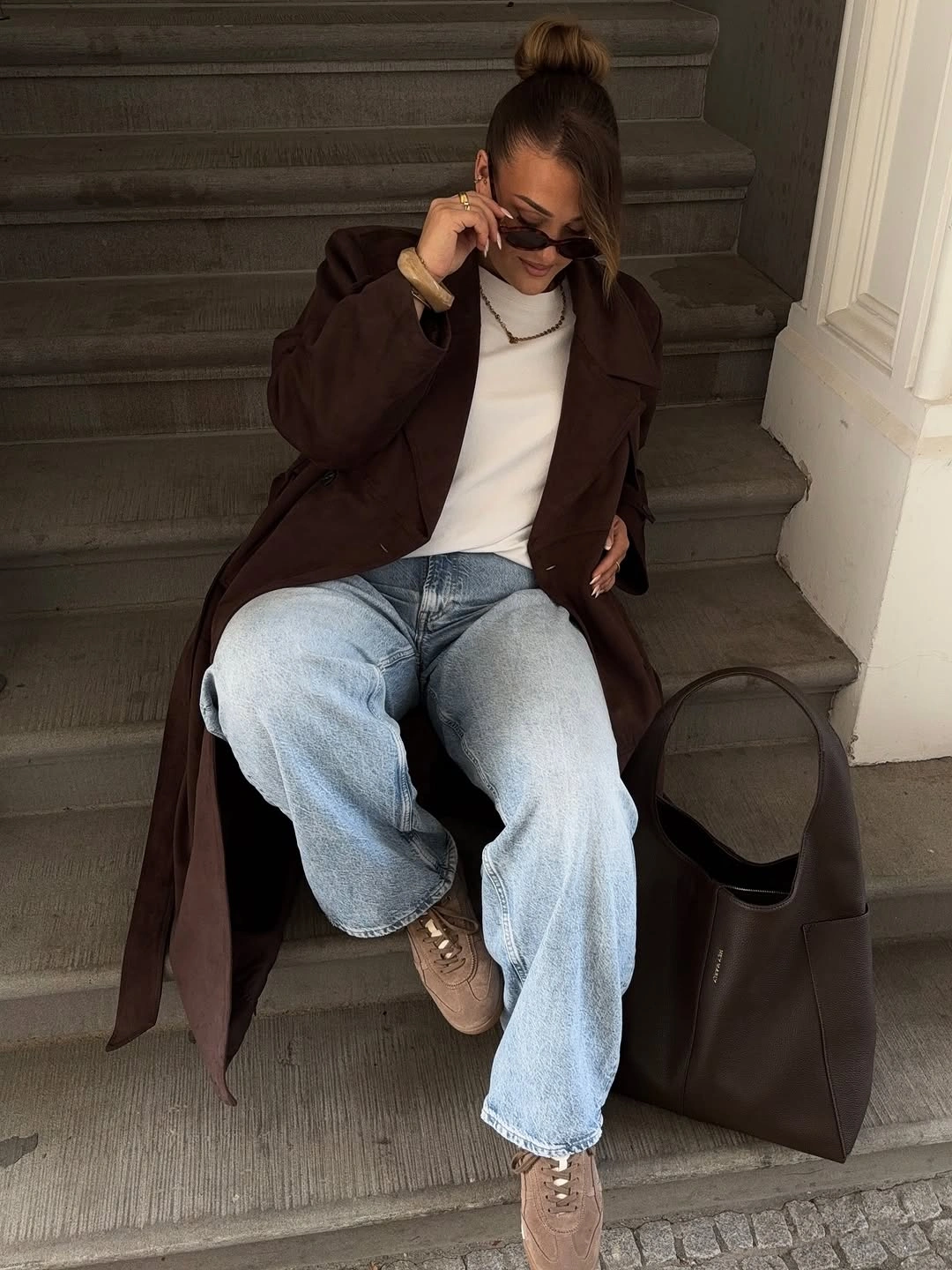 Long brown coat with white top and wide light jeans