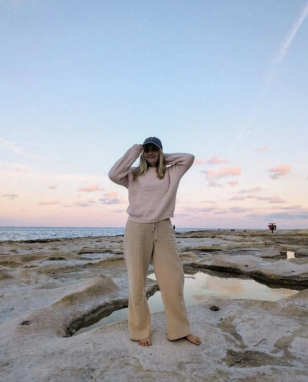 Blush sweatshirt with beige wide-leg pants and dark baseball cap