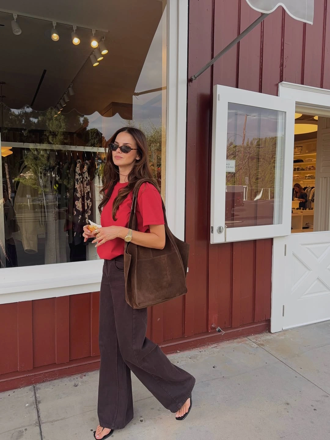 Red short-sleeve top with chocolate trousers, brown tote, and sandals