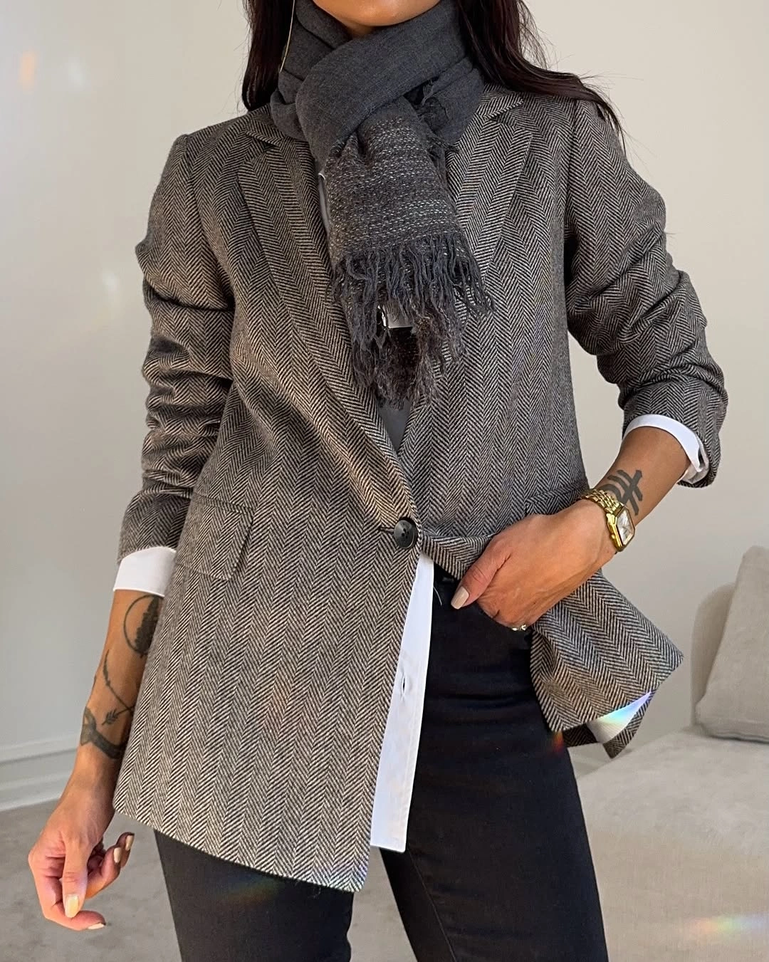 Gray herringbone-pattern blazer with white shirt, black trousers, and dark scarf