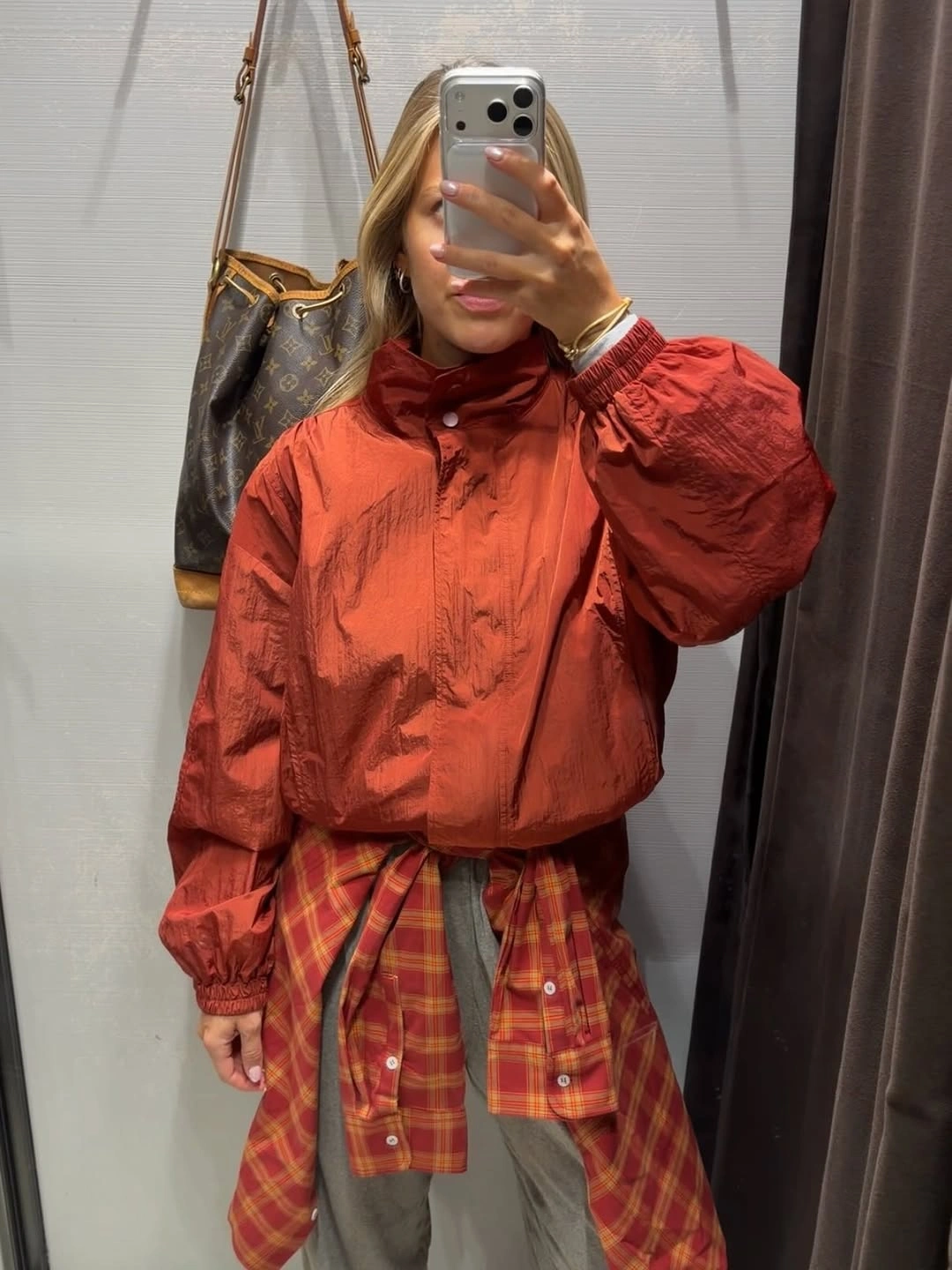 Rust jacket with plaid waist layer and pale gray trousers