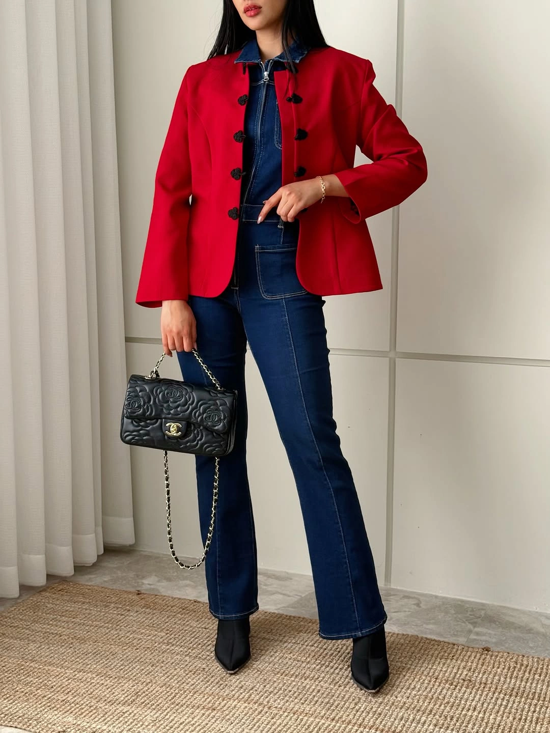 Red structured jacket over dark denim with black boots and bag