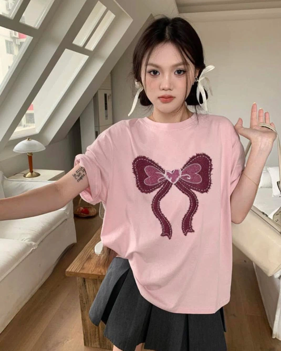Pink bow graphic T-shirt with dark pleated mini skirt and ribbons