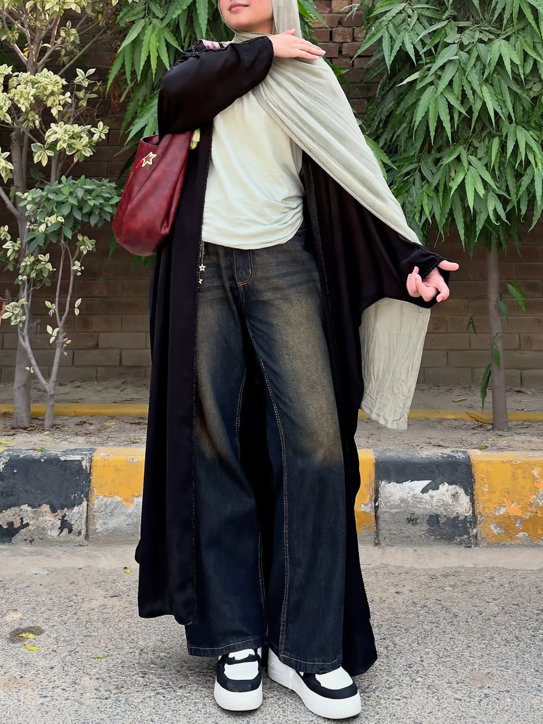 Long black layer with pale drape, dark jeans, and chunky sneakers