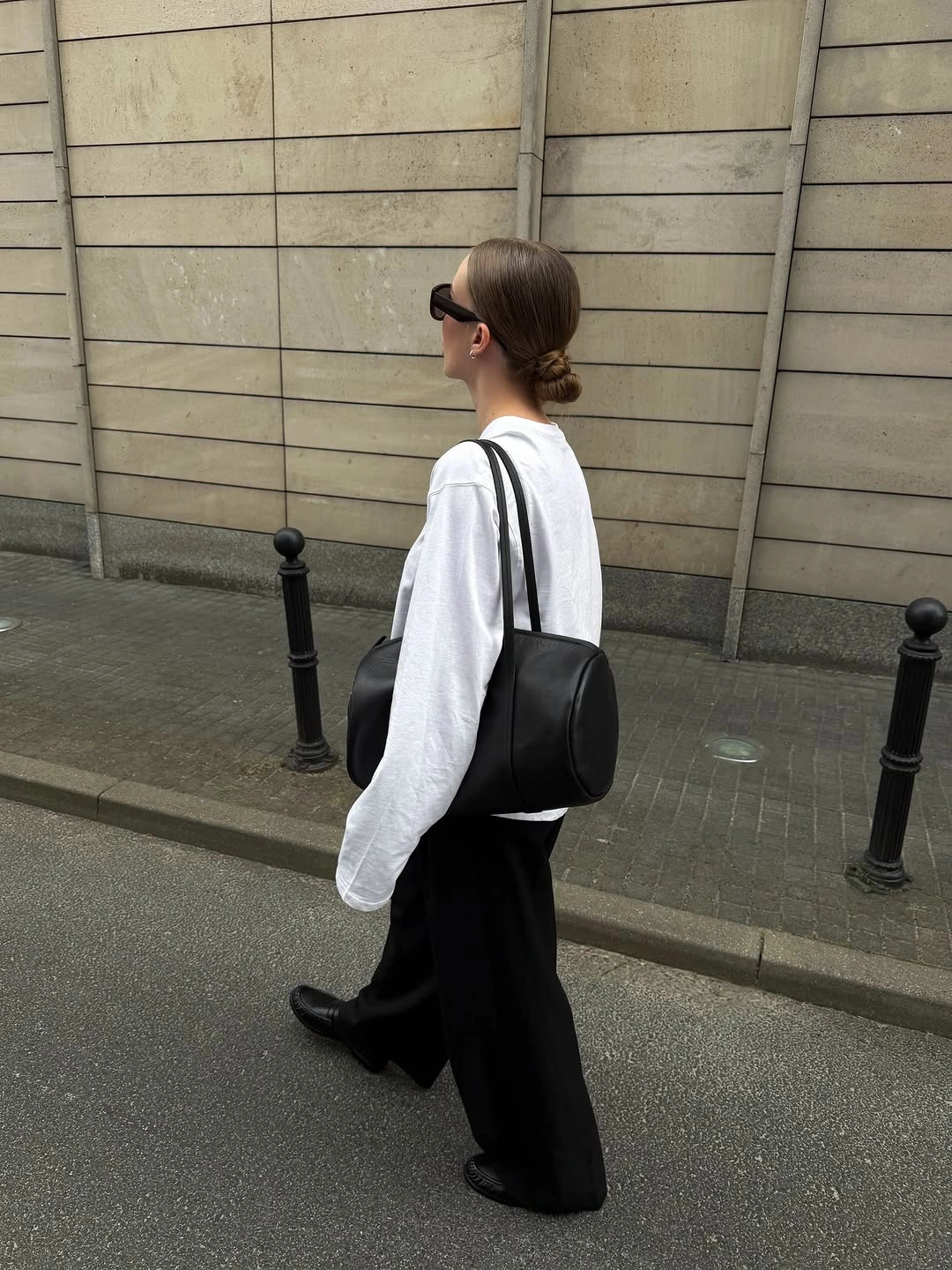 Oversized white button-down with loose black trousers and shoulder bag