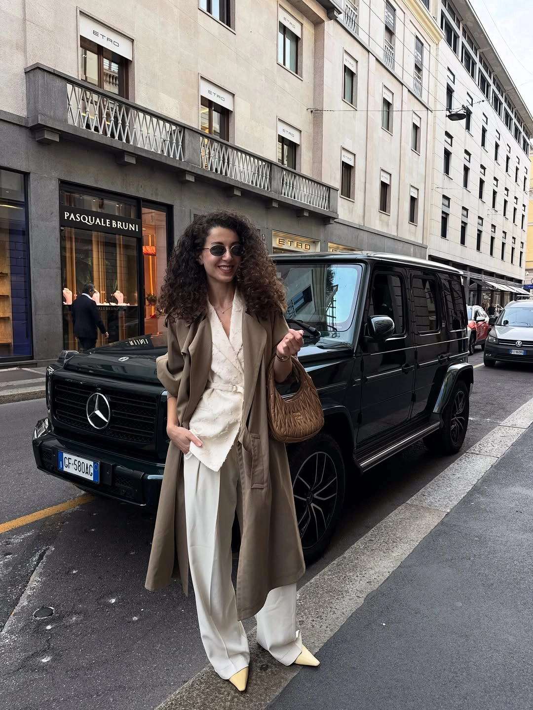 Taupe long coat with white trousers and yellow pointed shoes