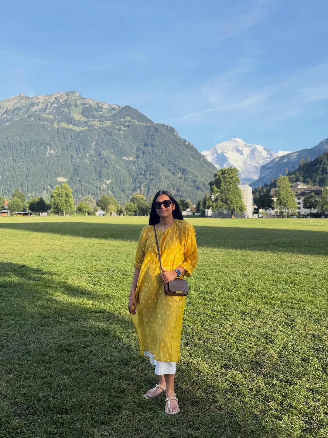 Yellow patterned dress layered over white cropped trousers