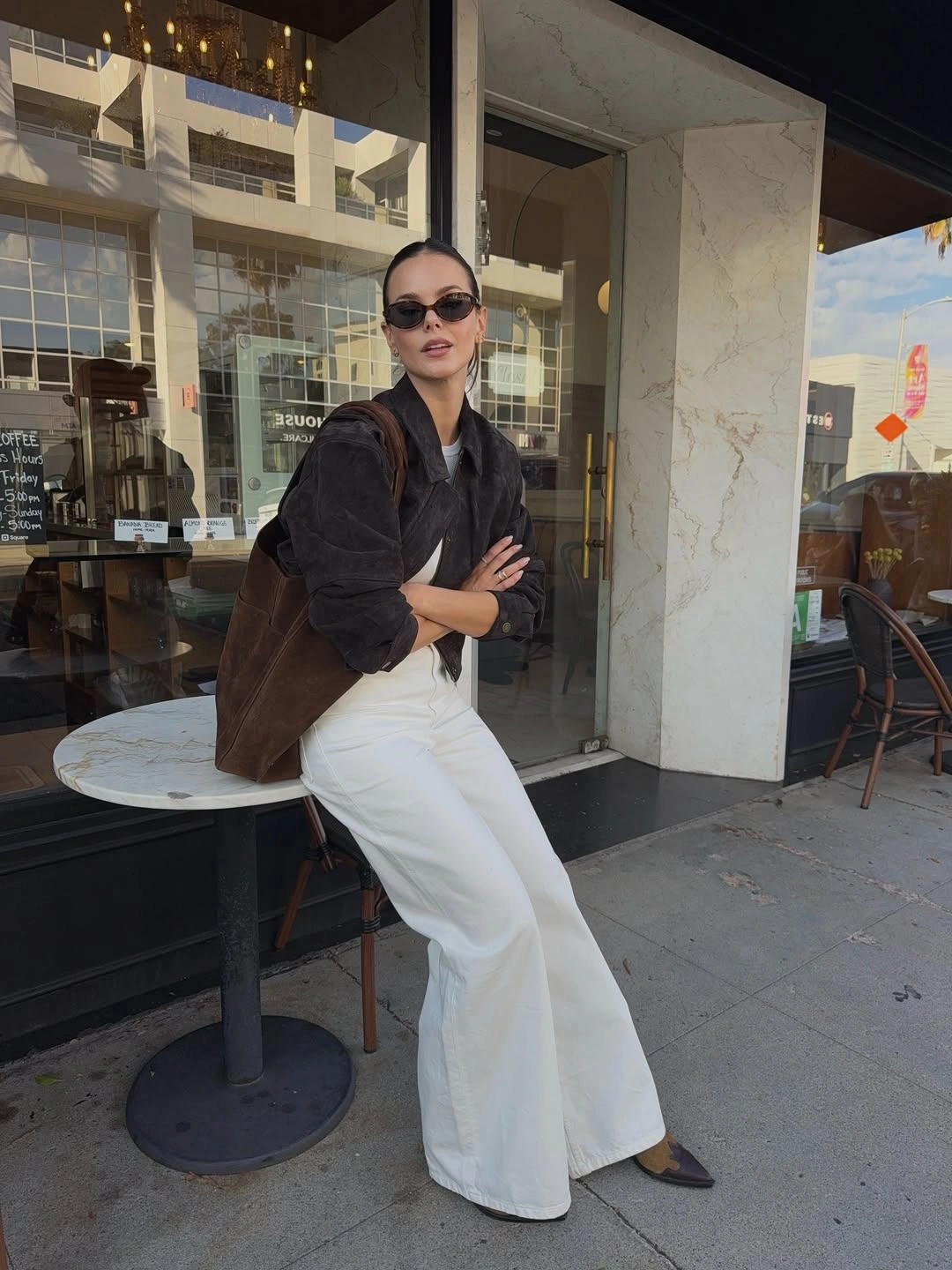Dark brown jacket with wide white trousers and shoulder bag