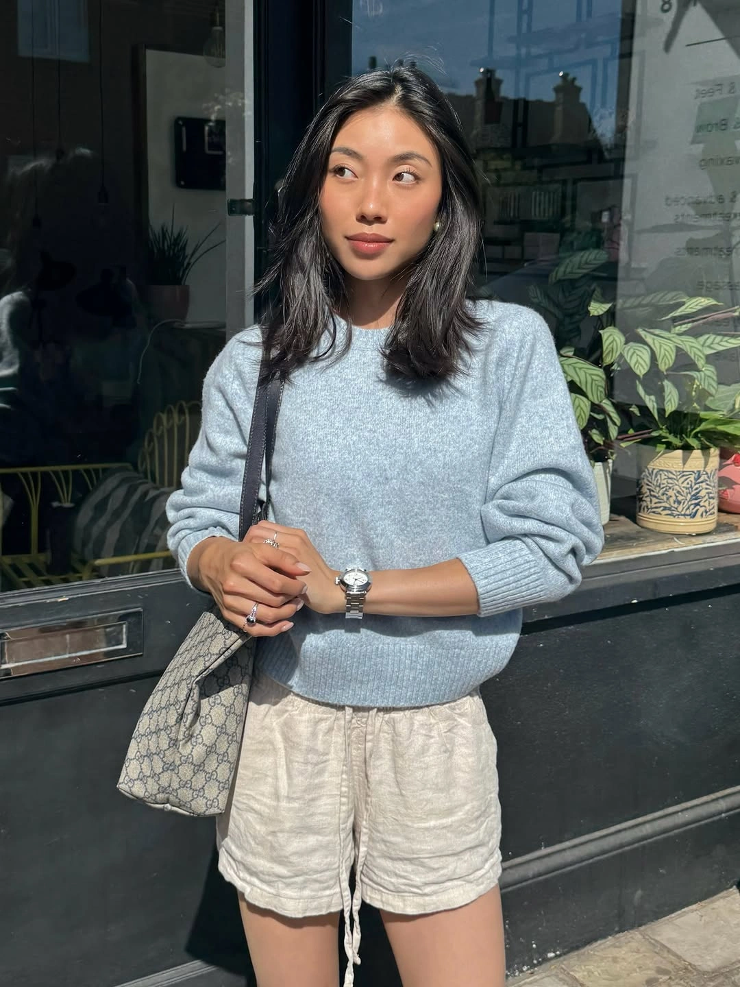 Pale blue sweater with cream drawstring shorts and patterned bag