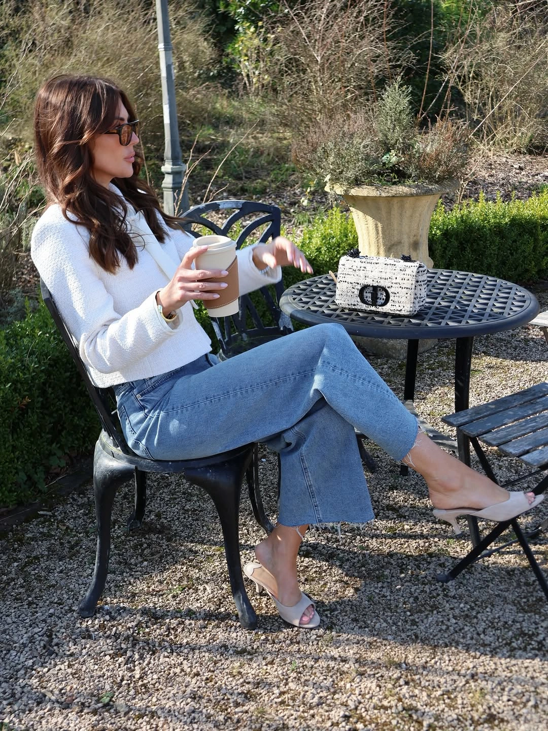 Seated woman in white top, cropped blue jeans, and open-toe heels