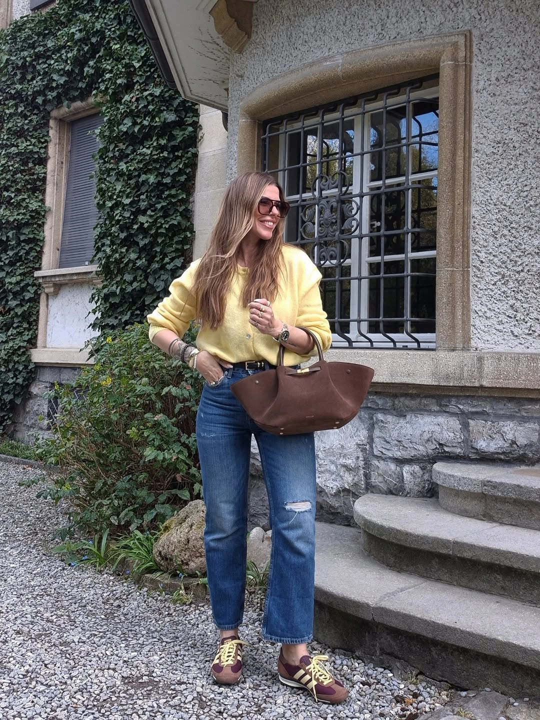 Woman in yellow top, straight jeans, brown bag, and multicolor shoes