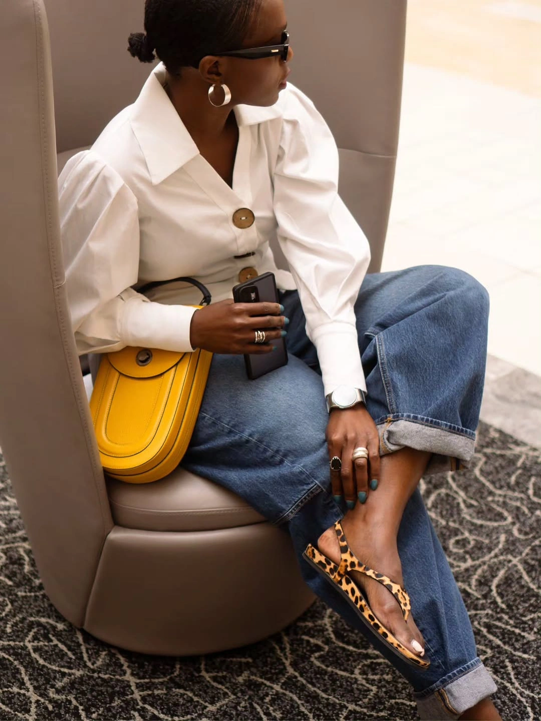 Woman in cuffed jeans, white blouse, beige layer, and yellow bag