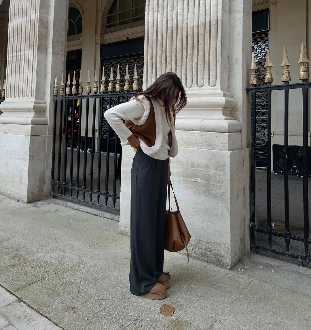 Cream top with camel-toned shoulder drape, charcoal trousers, and brown bag
