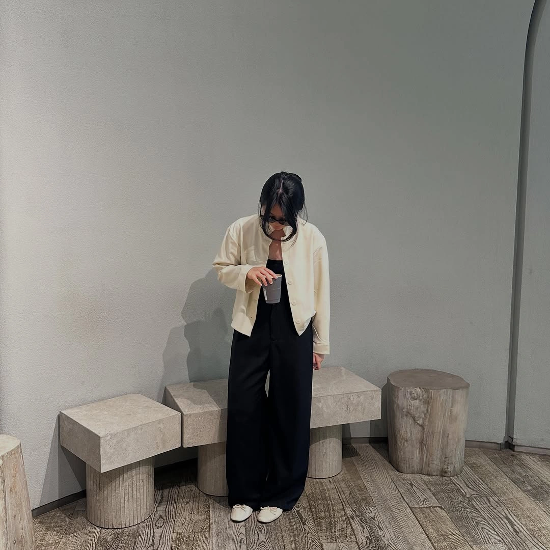 Short ivory button-front jacket with wide black trousers and white shoes