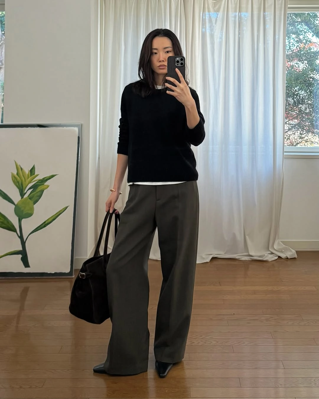 Black relaxed sweater with white underlayer, olive trousers, and pointed shoes