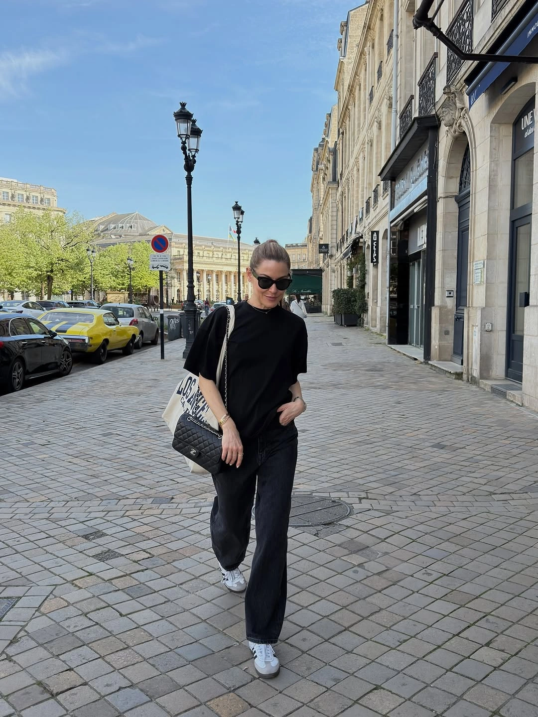 Black short-sleeve T-shirt with dark jeans, white sneakers, and canvas tote