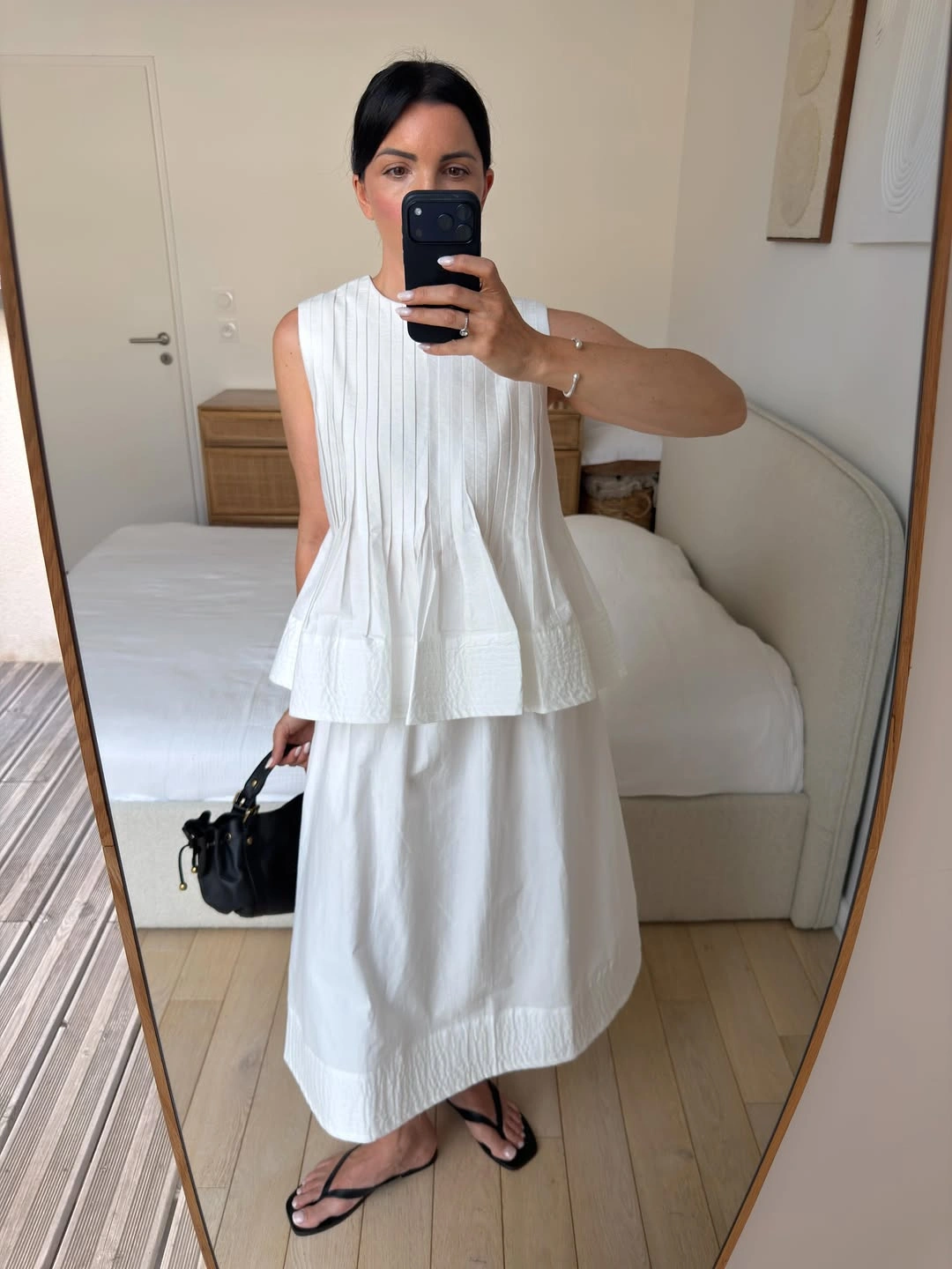 Sleeveless pleated white top and long white skirt with black accessories