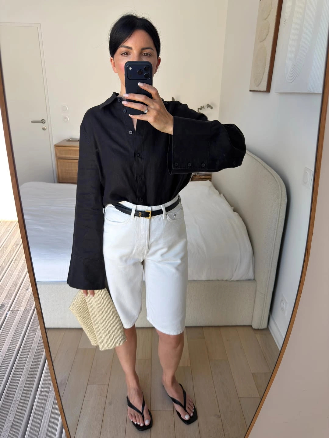 Black button-front shirt with white knee-length shorts, slim belt, and flip-flops