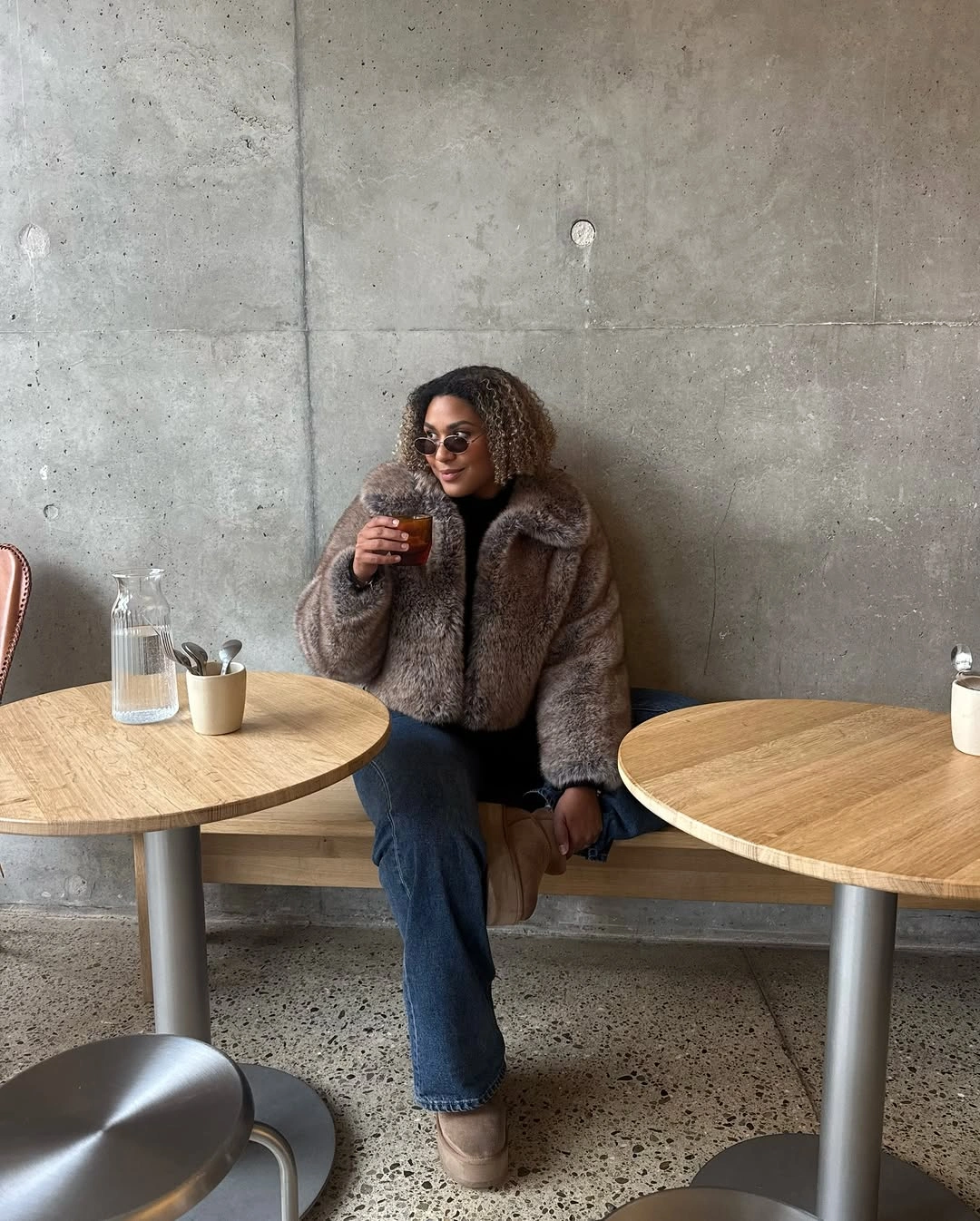 Shaggy gray-brown jacket with blue jeans, taupe footwear, and sunglasses