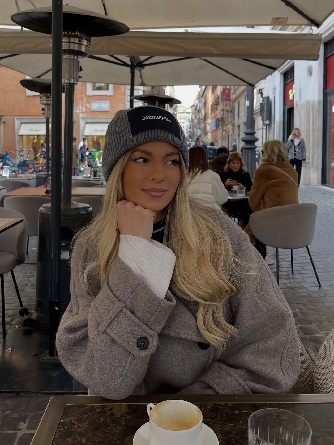 Woman in gray coat, black knit cap, and pale sleeves