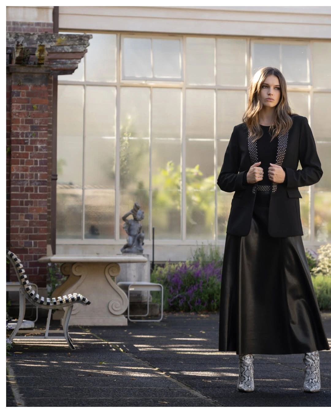 Woman in black blazer and long dark skirt wearing silver patterned boots