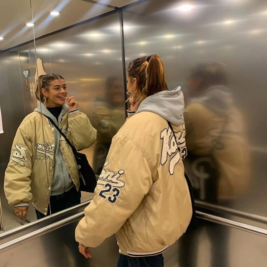 Oversized cream graphic jacket layered over gray hoodie and jeans