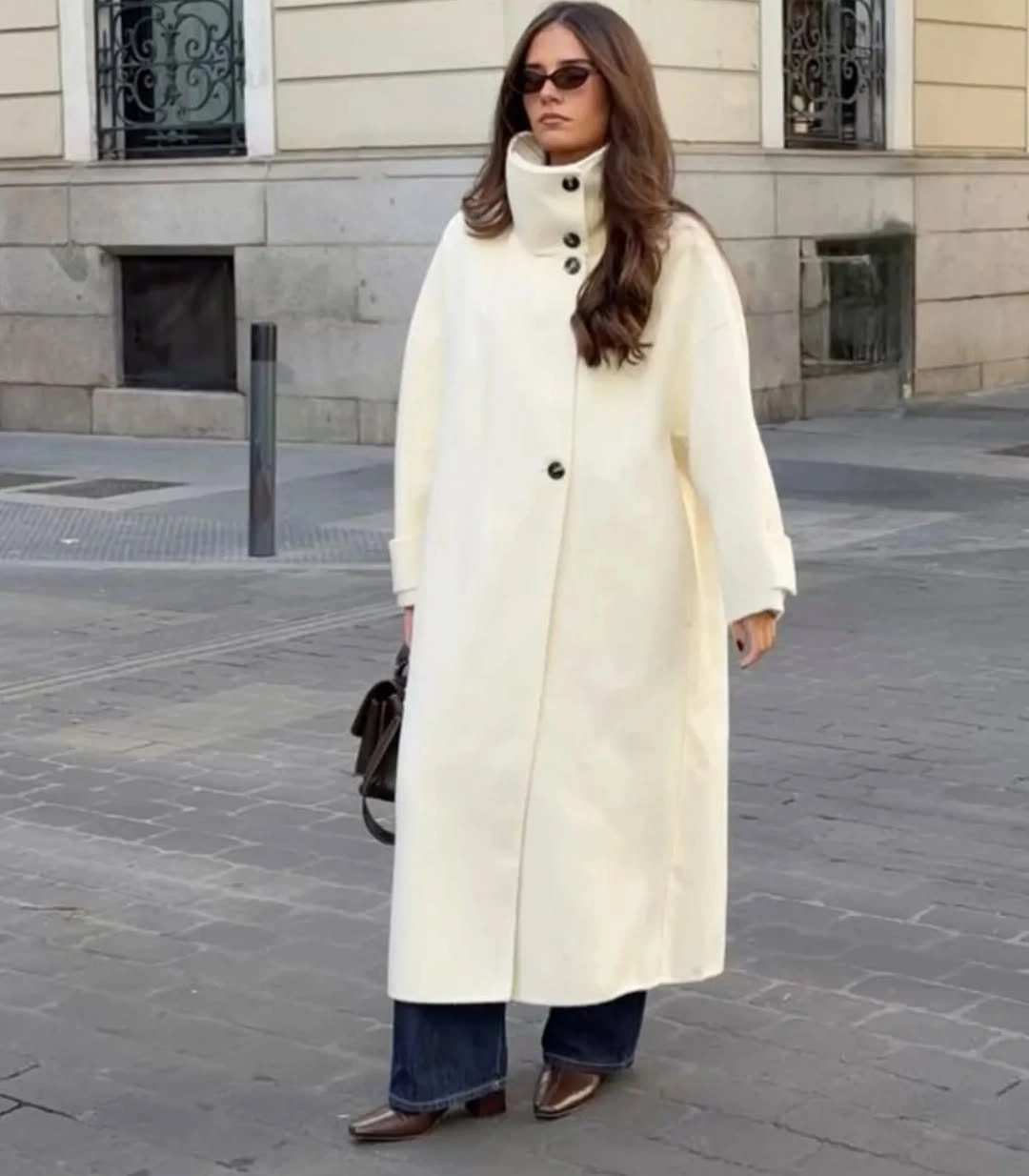 Long ivory stand-collar coat above blue wide-leg trousers and pointed shoes