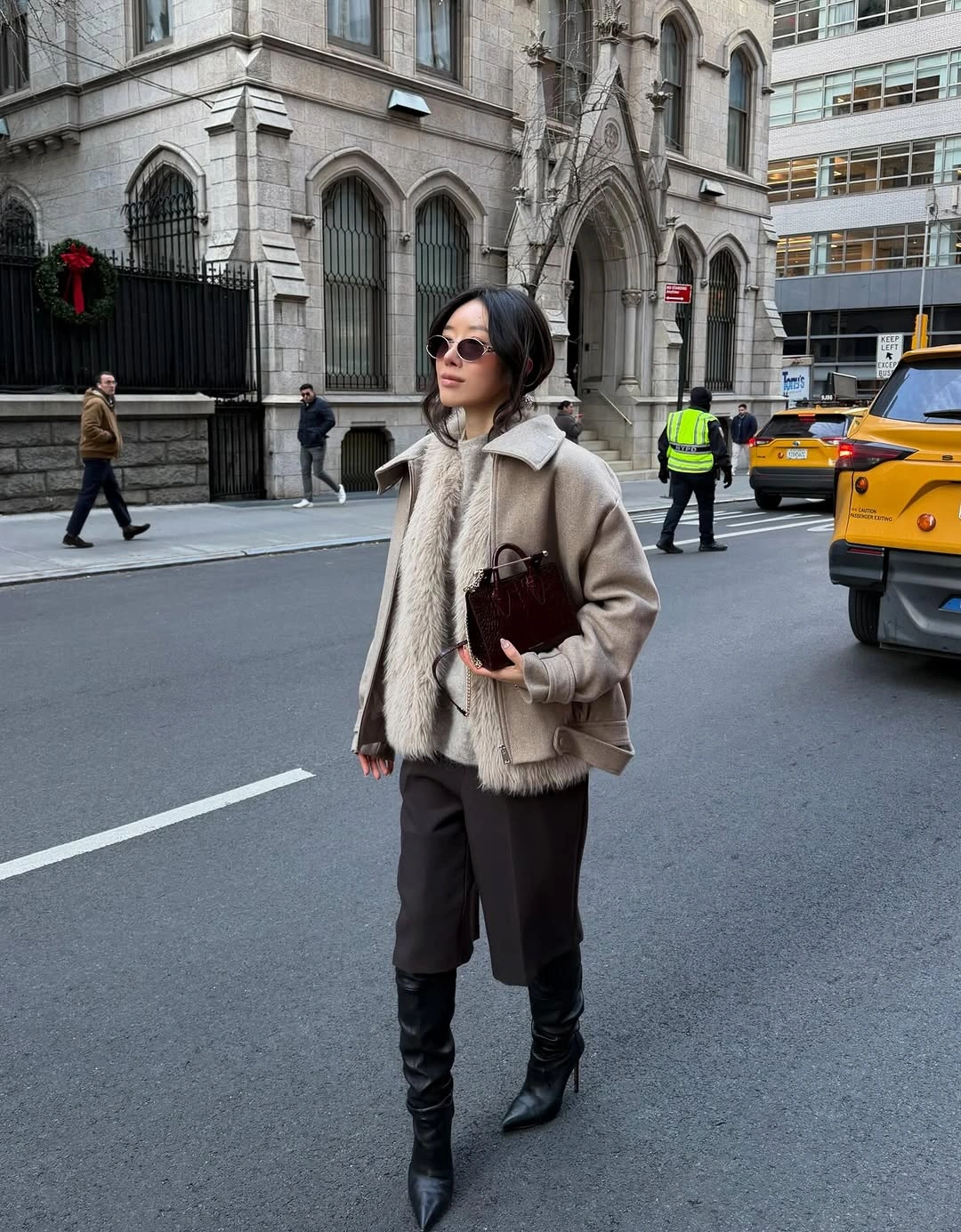 Taupe jacket with shaggy cream front, dark trousers, and pointed boots