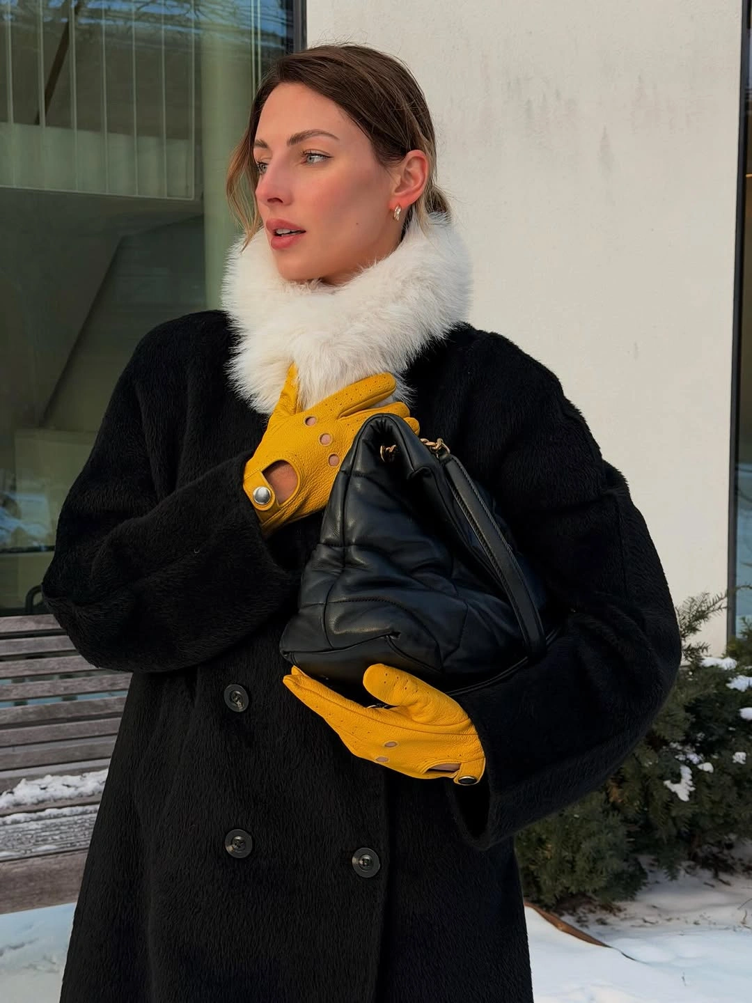 Black double-breasted coat with fluffy white neck detail and yellow gloves