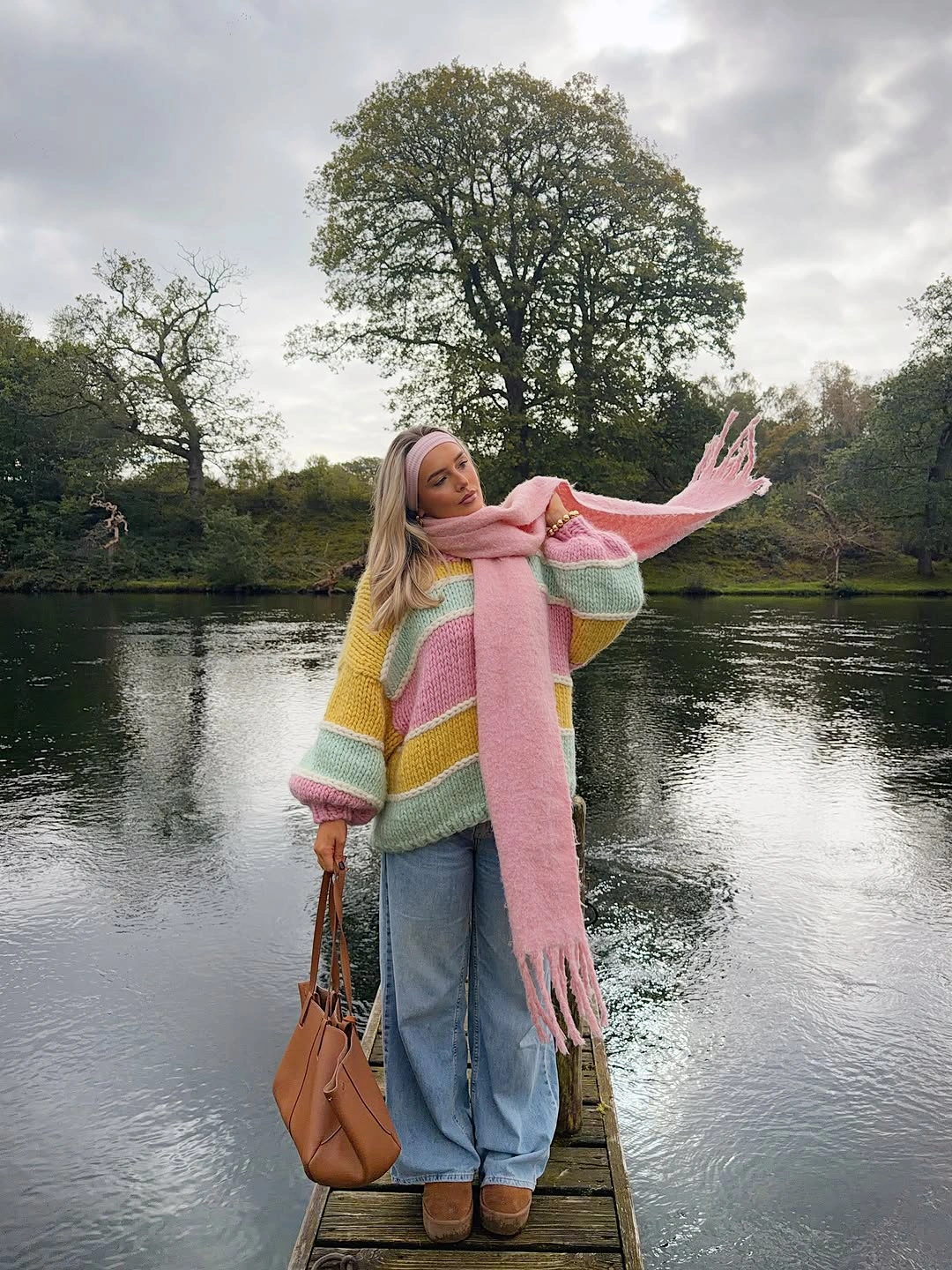 Multicolored pastel knit with pink scarf loose jeans and tan handbag