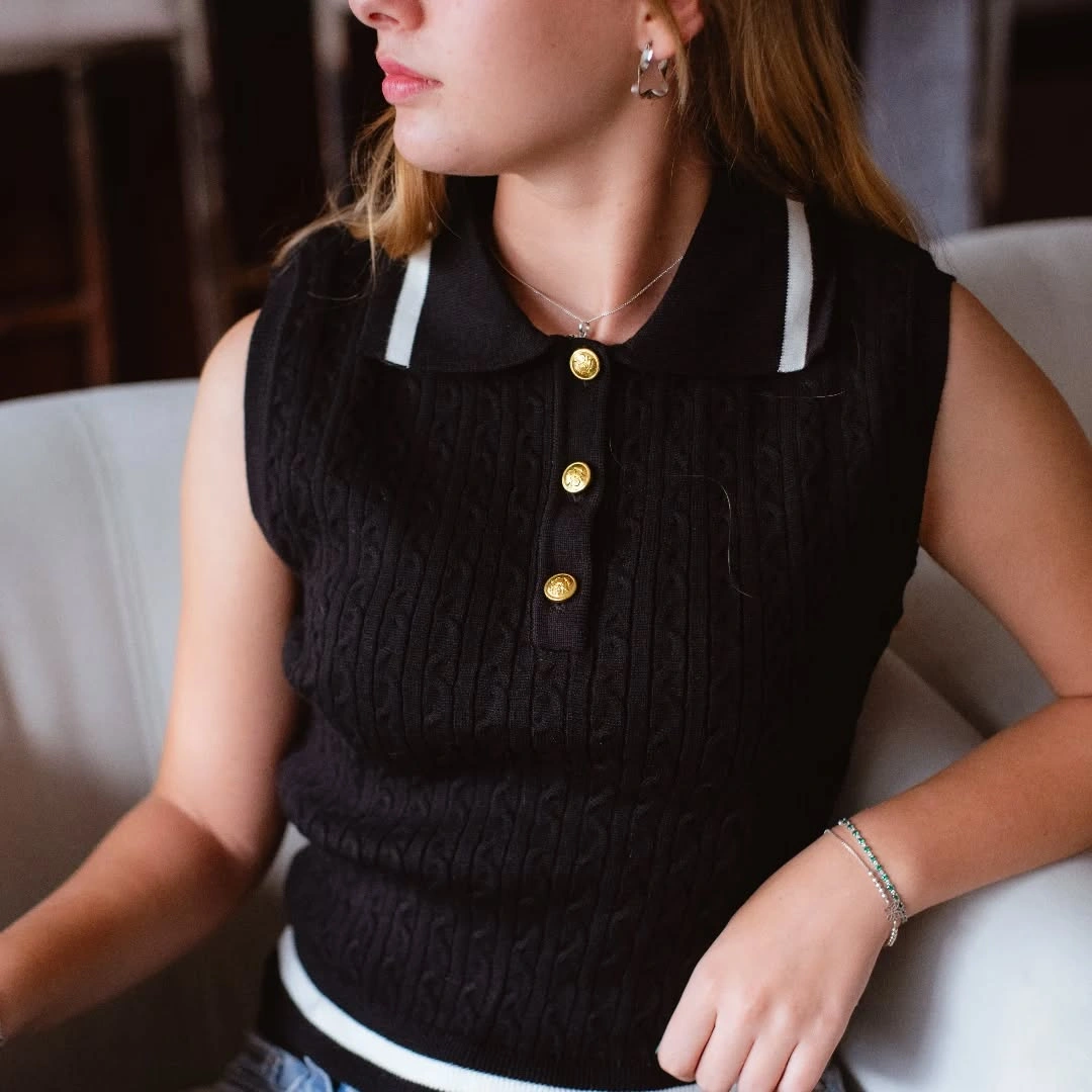 Black sleeveless cable knit with white trim and gold buttons
