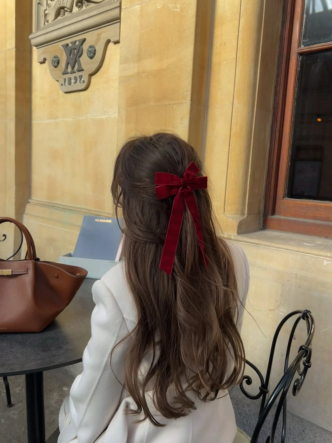 Long brown hair with burgundy ribbon bow and pale jacket