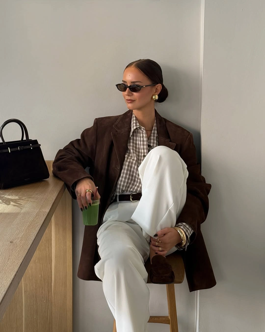 Oversized brown blazer checked shirt white trousers and dark handbag