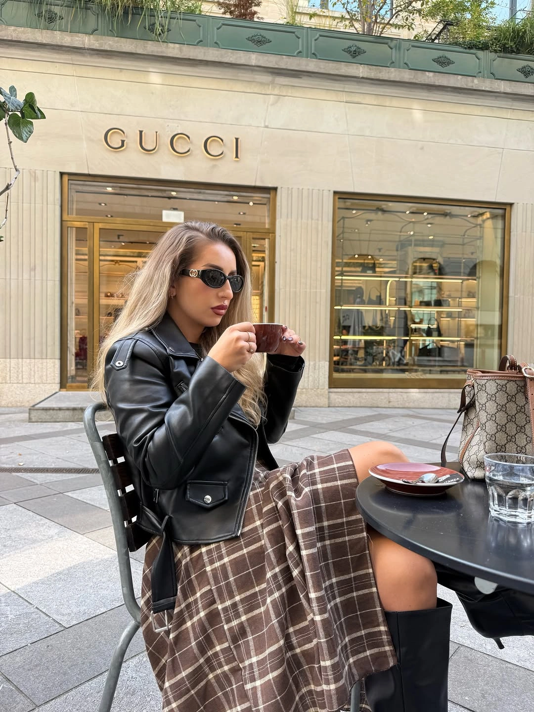 Black leather-look biker jacket brown plaid skirt and knee-high boots