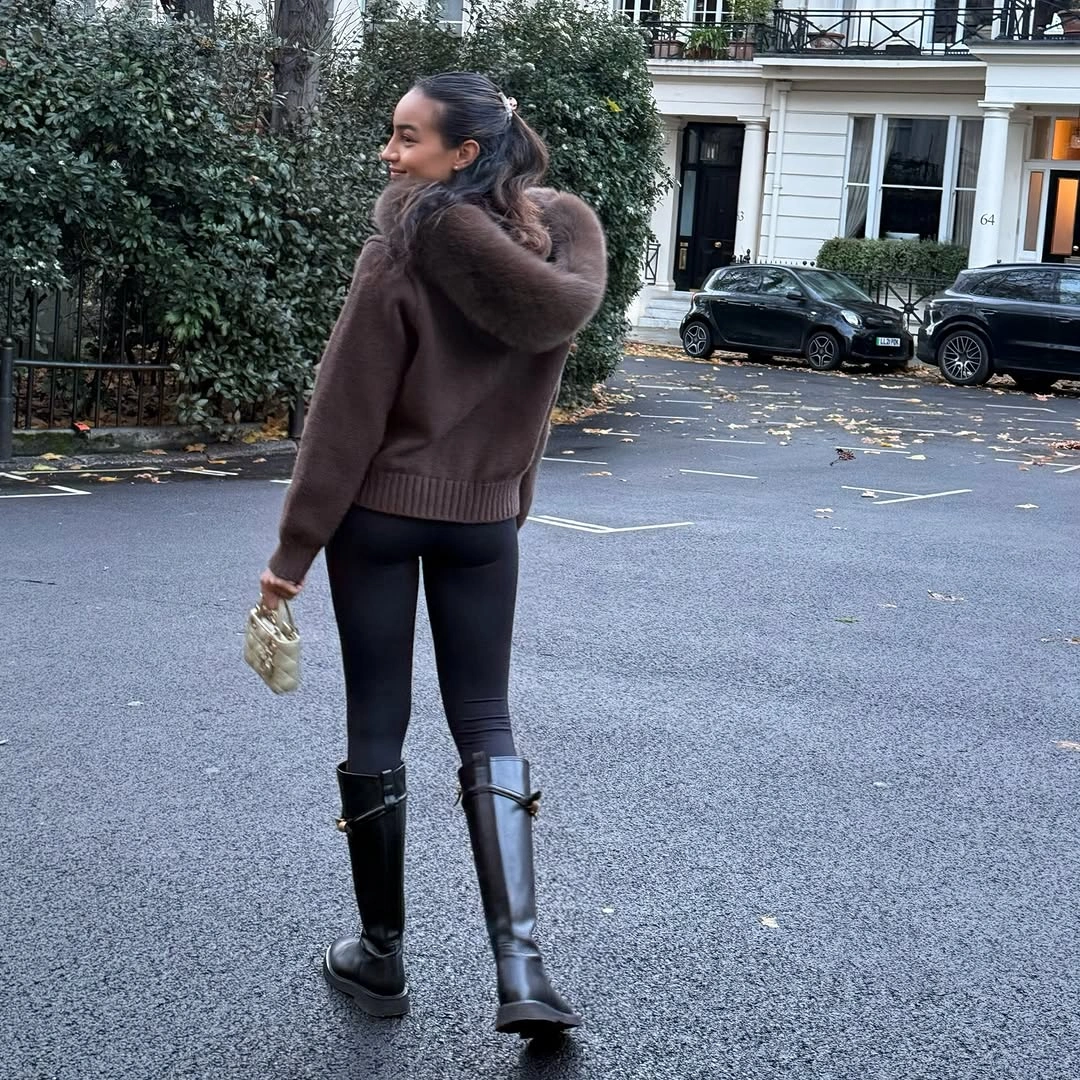 Brown hooded knit with fluffy trim black leggings and tall buckled boots