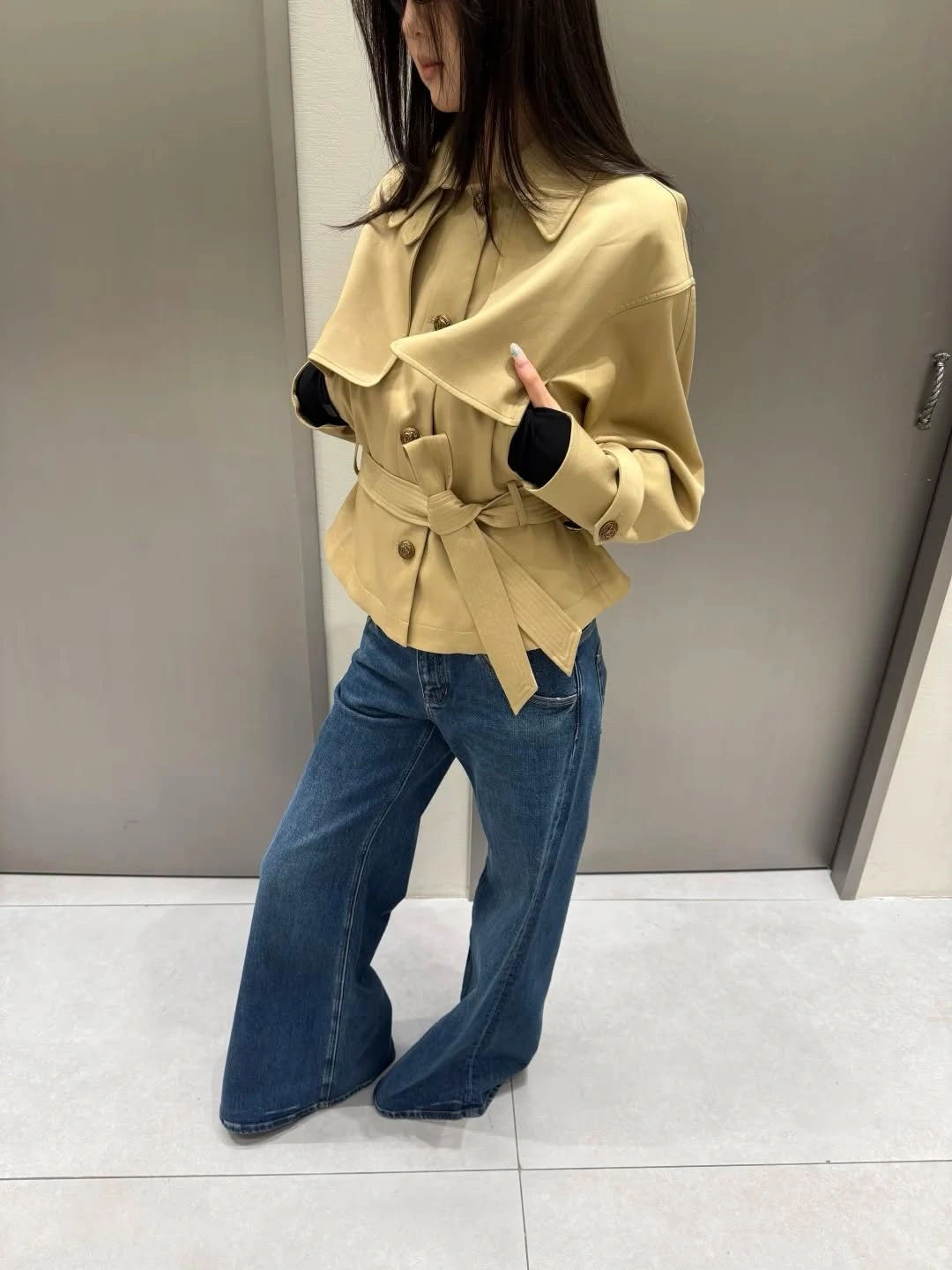 Pale mustard belted jacket with folded collar and wide blue jeans